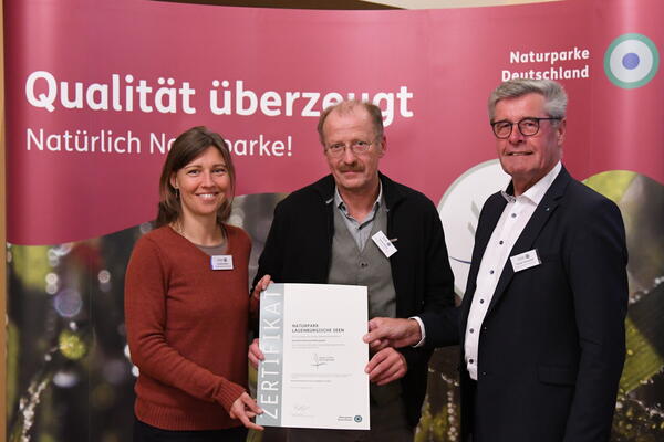 Frank Hadulla und Claudia Rösen vom Naturpark Lauenburgische Seen freuen sich über die erneute Auszeichnung und nehmen die Urkunde von VDN-Präsident Friedel Heuwinkel entgegen.